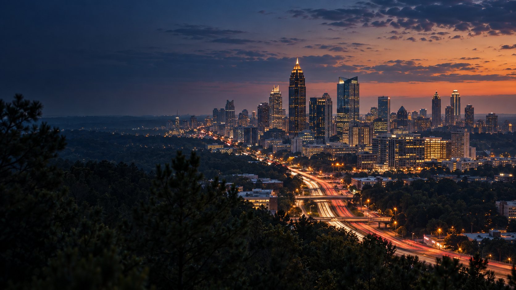Atlanta skyline at dusk seen across the treeline and the interstate.