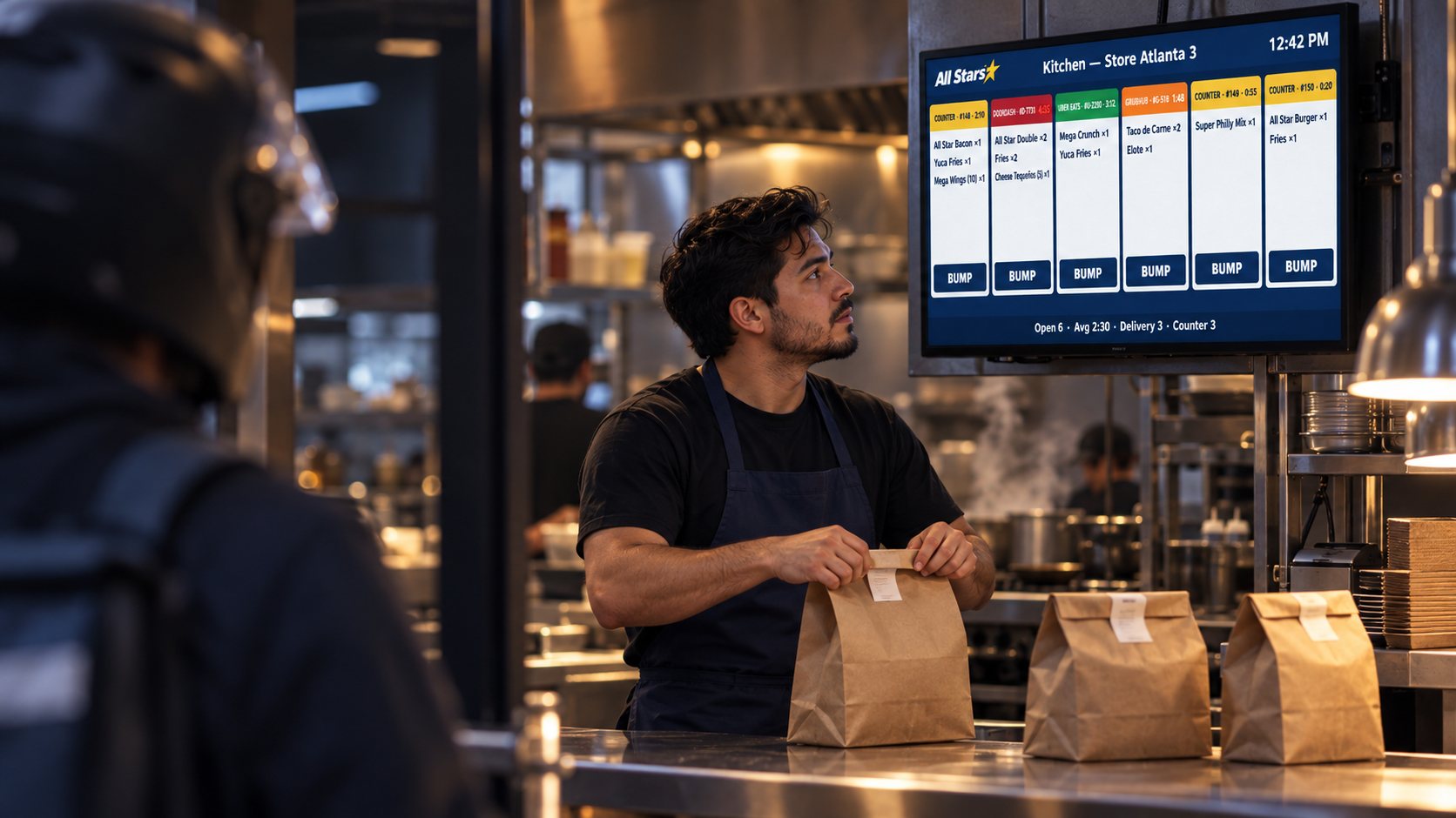 Delivery courier collecting bagged orders at the counter while the kitchen display shows the queue.